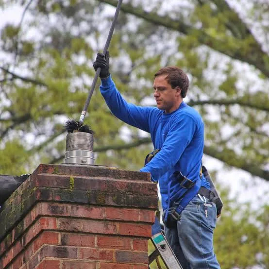 Technician brushing a masonry chimney from the roof