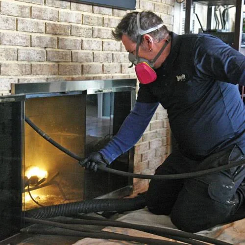 Fireplace technician using vacuum equipment during residue removal